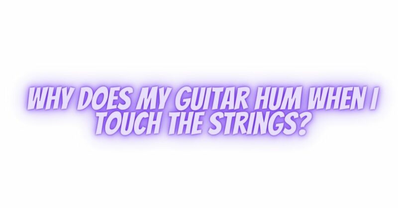 Why does my guitar hum when I touch the strings?